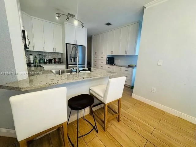 a kitchen with stainless steel appliances granite countertop a sink refrigerator and cabinets