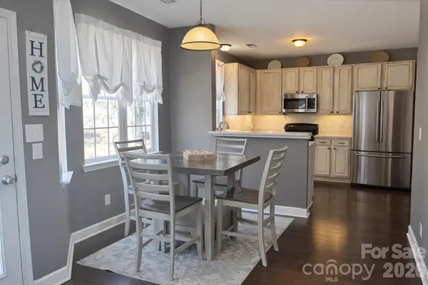 a kitchen with stainless steel appliances granite countertop a dining table chairs refrigerator and microwave
