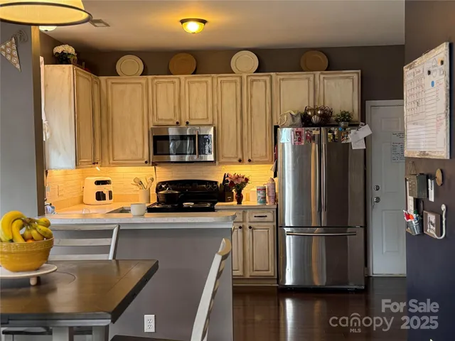 a kitchen with stainless steel appliances a refrigerator a stove a sink cabinets and a dining table