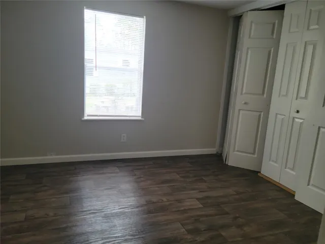 an empty room with wooden floor and window