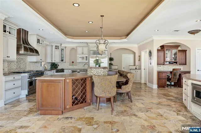 a large kitchen with kitchen island a counter a sink stainless steel appliances and cabinets