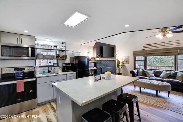 a large kitchen with sink a refrigerator and chairs