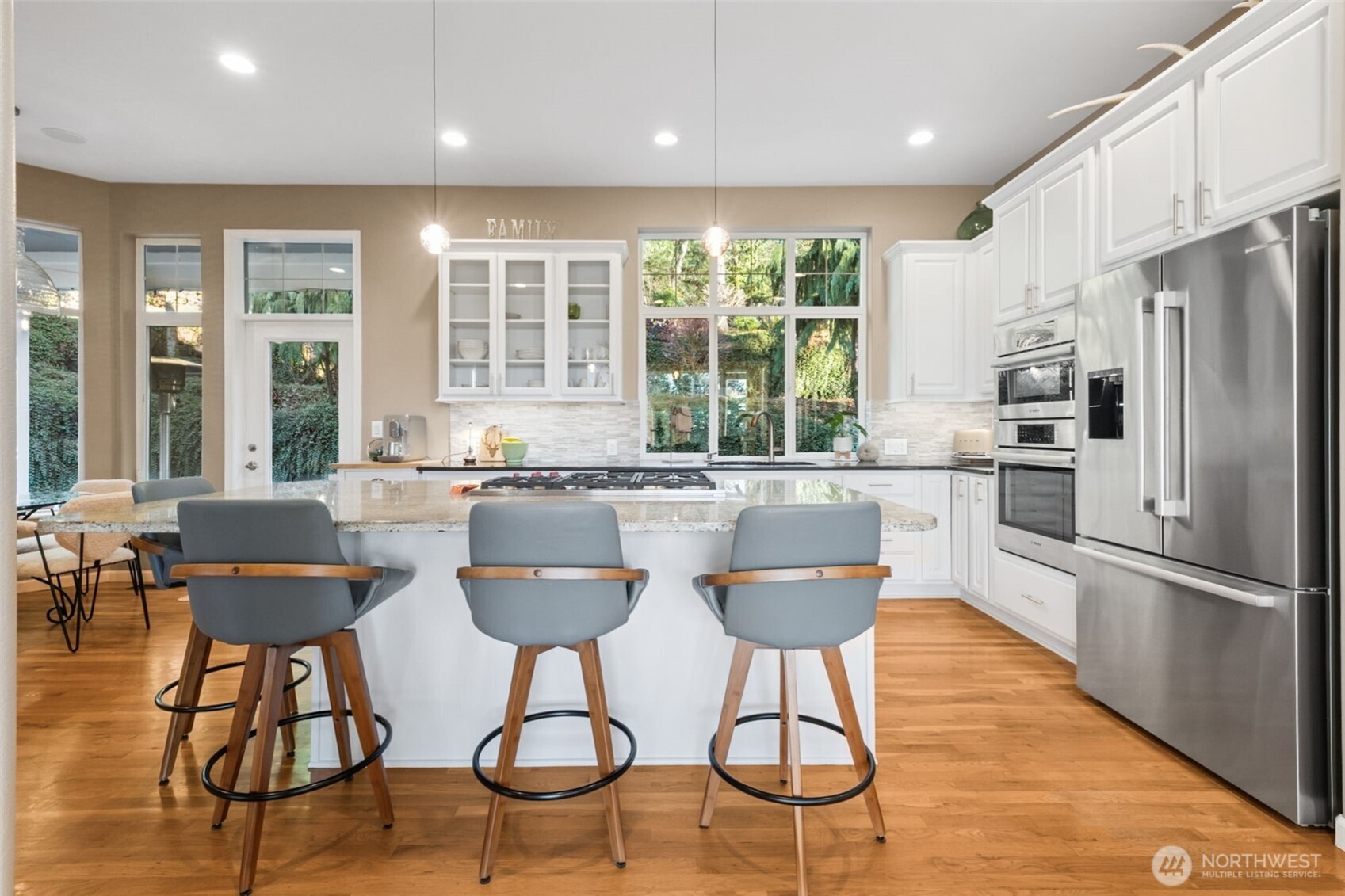 25913 Southeast 159th Street Issaquah, WA 98027 - Photo 15 of 40 a kitchen with stainless steel appliances granite countertop a table chairs refrigerator and wooden cabinets