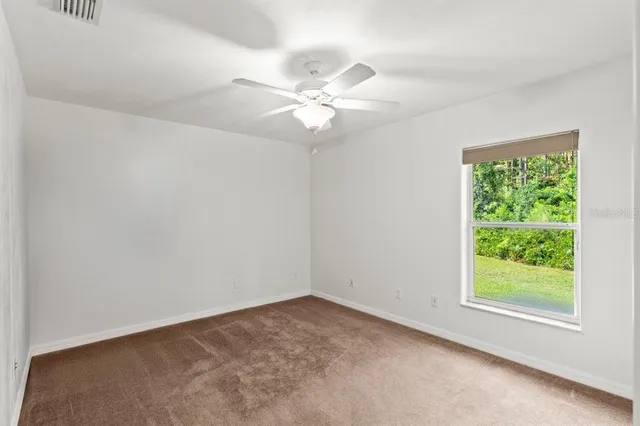a view of an empty room and chandelier fan