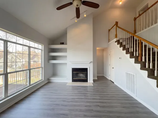 an empty room with wooden floor fireplace and windows