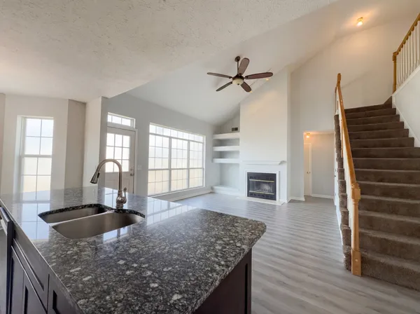 a kitchen with granite countertop a sink a counter top space and cabinets