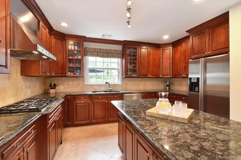 a kitchen with stainless steel appliances granite countertop a sink a stove a refrigerator cabinets and living room view