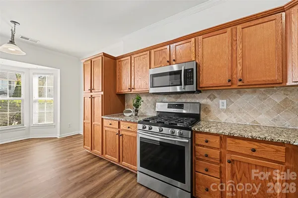 a kitchen with granite countertop wooden cabinets stainless steel appliances and a window