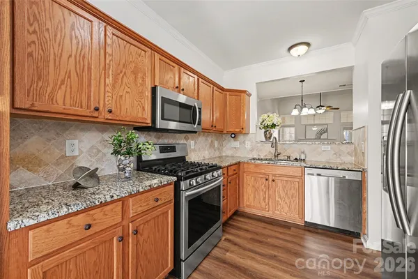 a kitchen with stainless steel appliances granite countertop a stove top oven a sink dishwasher a refrigerator and a microwave oven