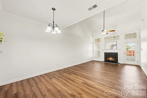 a view of an empty room with wooden floor fireplace and a window