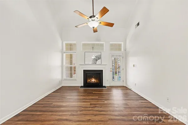 a view of an empty room with wooden floor fireplace and a window