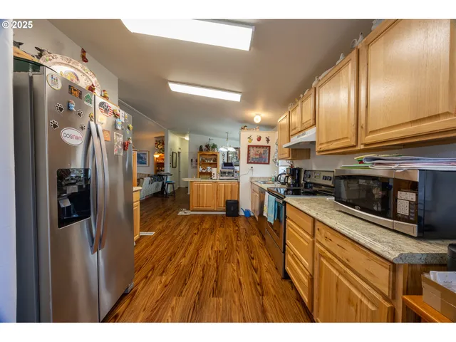 a kitchen with stainless steel appliances granite countertop a refrigerator a stove and a wooden floor