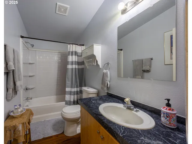 a bathroom with a granite countertop sink toilet mirror and shower