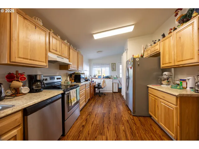 a kitchen with granite countertop a refrigerator stove sink and cabinets