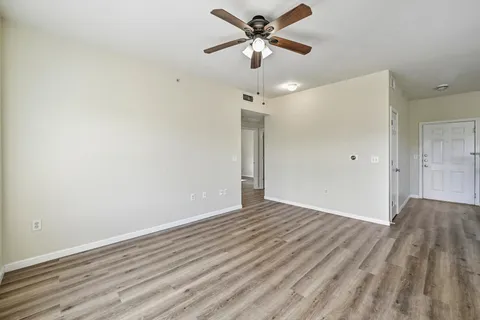 a view of empty room with wooden floor and fan