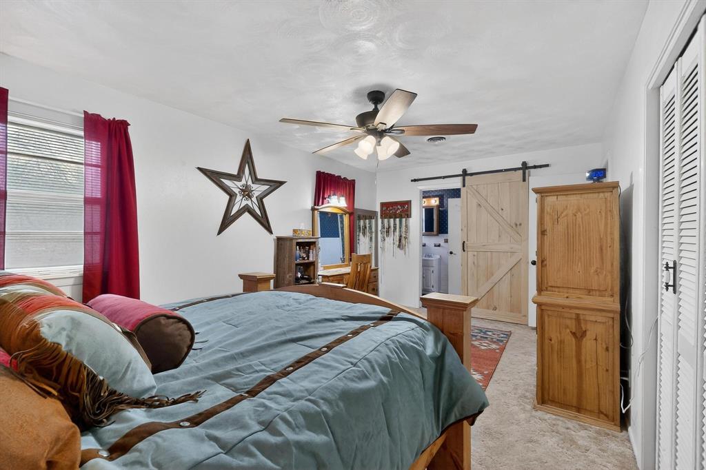 202 Senter Valley Road Irving, TX 75060 - Photo 19 of 32 Bedroom featuring a ceiling fan with light fixture, window with horizontal blinds, and a sliding barn door