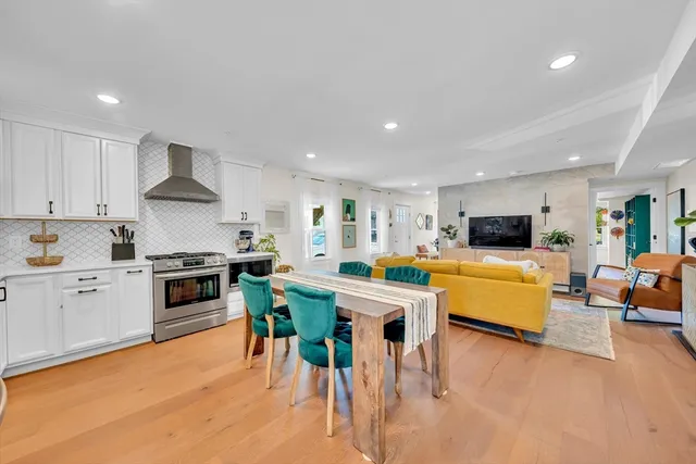 a kitchen with stainless steel appliances granite countertop a stove top oven a sink dishwasher a dining table and chairs with wooden floor