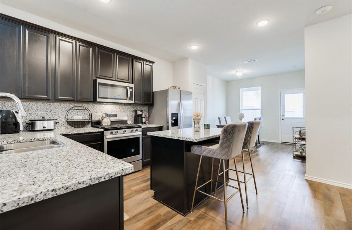 25535 Pitchfork Ranch Place Katy, TX 77493 - Photo 3 of 25 a kitchen with stainless steel appliances granite countertop a stove a sink a microwave a dining table and chairs