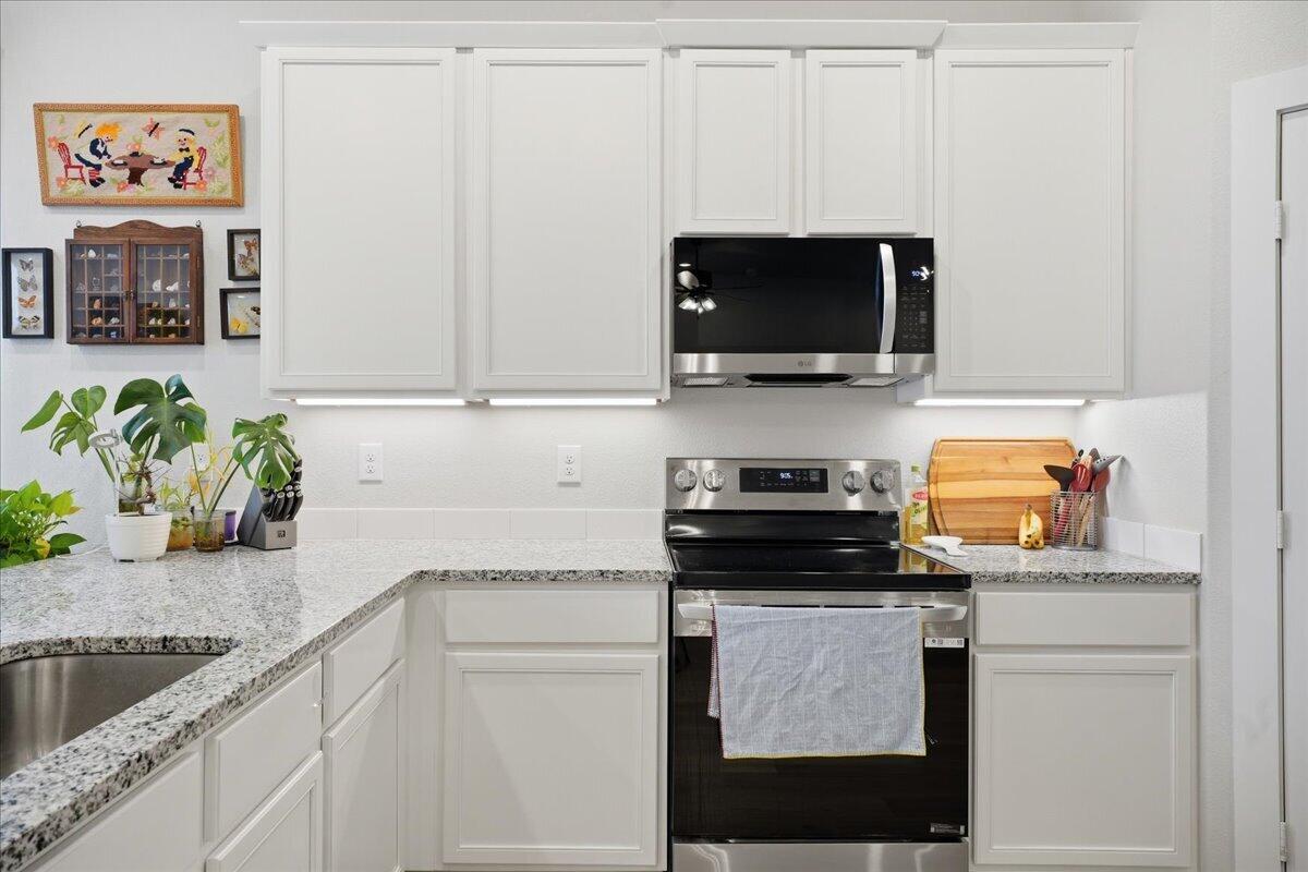 7416 30th Street Lubbock, TX 79407 - Photo 11 of 31 a kitchen with stainless steel appliances granite countertop a stove and a microwave