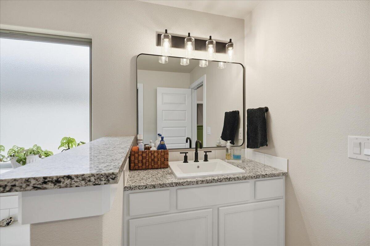 7416 30th Street Lubbock, TX 79407 - Photo 19 of 31 a bathroom with a granite countertop sink and a mirror
