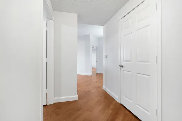 an empty room with wooden floor fan and windows