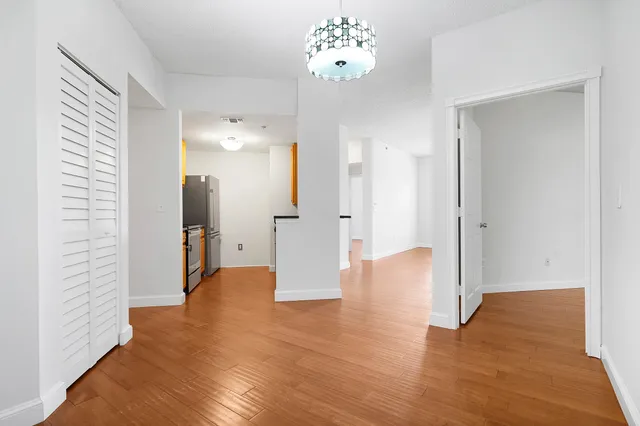 a view of an empty room with wooden floor and a bathroom