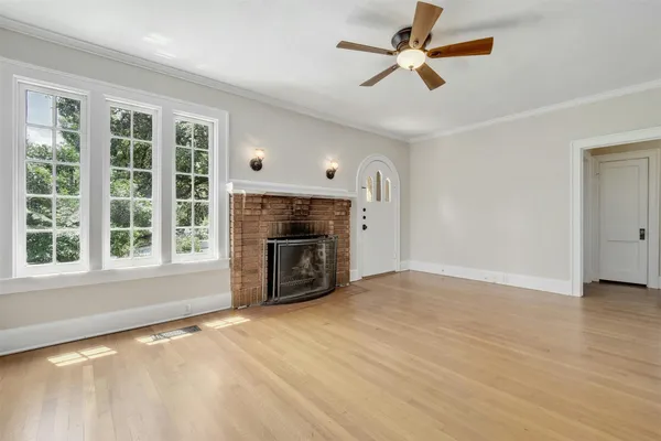 a view of empty room with a fireplace and a ceiling fan
