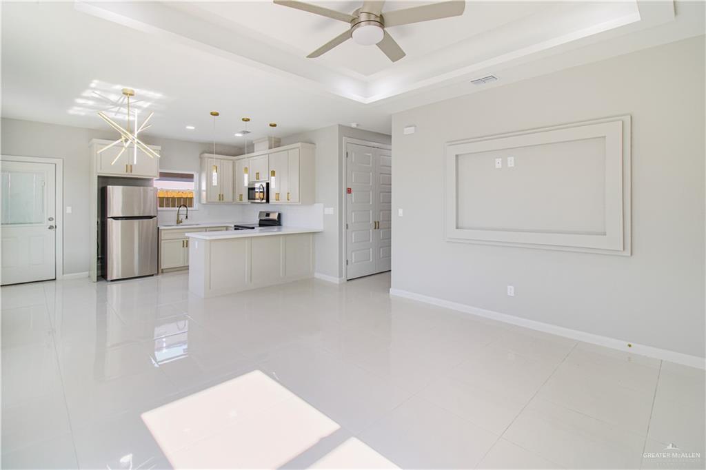 2002 East 1st Street, Unit 2 Mission, TX 78572 - Photo 5 of 15 Kitchen with light countertops, stainless steel appliances, white cabinets, a peninsula, and ceiling fan
