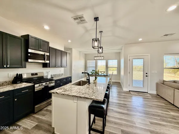 a kitchen with granite countertop stainless steel appliances and wooden floor
