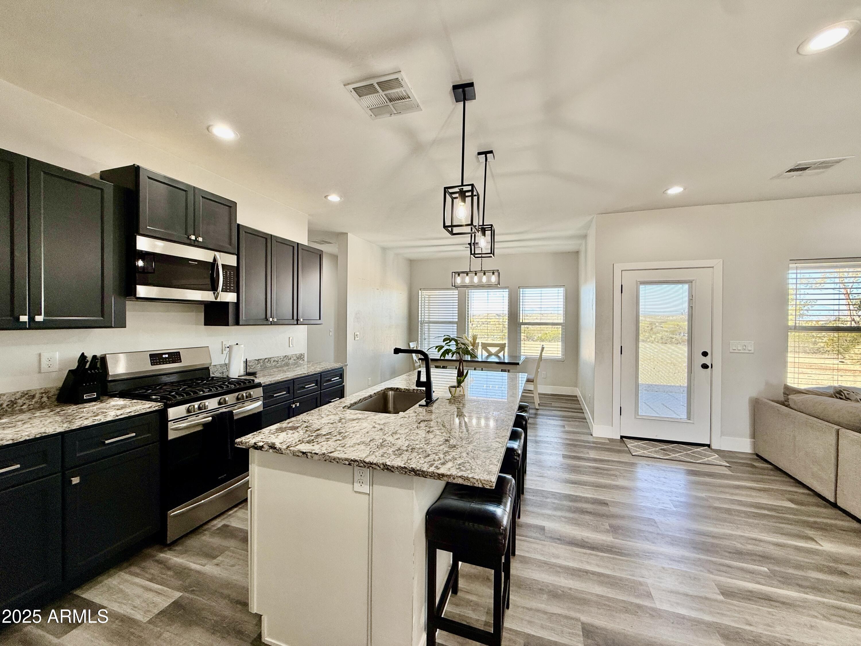 640 South 600 West Pima, AZ 85543 - Photo 3 of 22 a kitchen with granite countertop stainless steel appliances and wooden floor