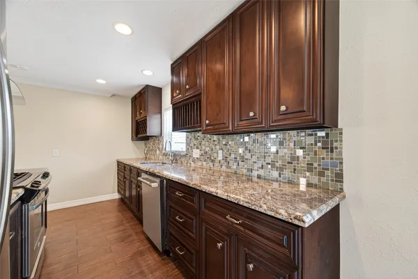 a kitchen with granite countertop wood cabinets and stainless steel appliances