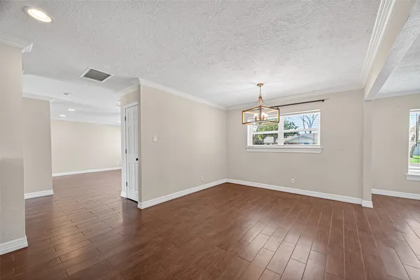 an empty room with wooden floor chandelier and windows