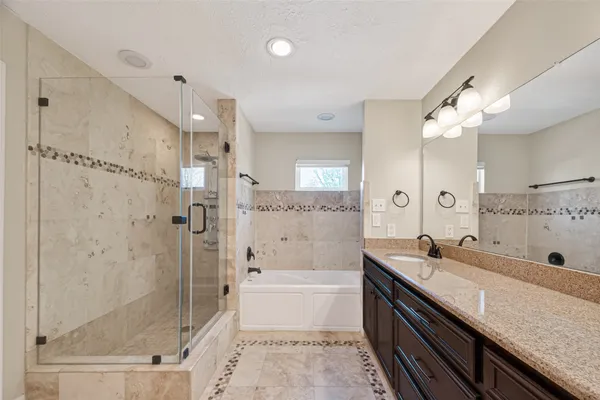 a bathroom with a granite countertop sink a mirror a bathtub and shower