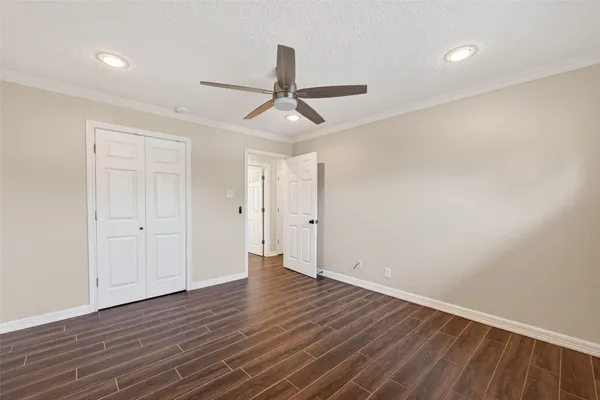 an empty room with wooden floor ceiling fan and windows
