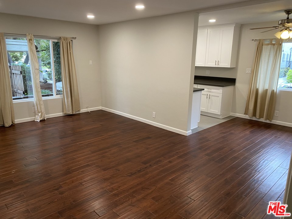 an empty room with wooden floor and a kitchen
