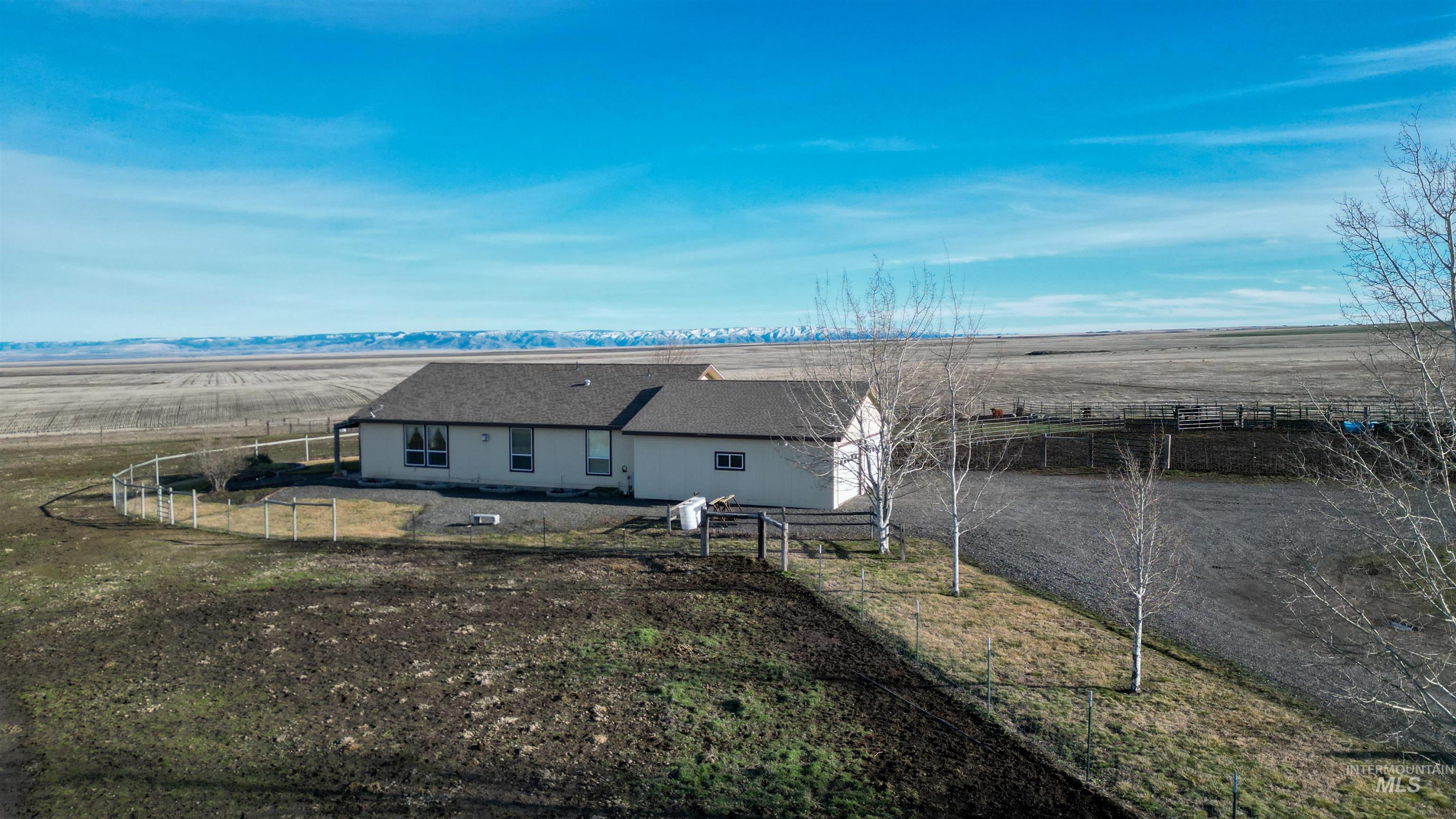 Back of property featuring a view of rural / pastoral area and a shingled roof