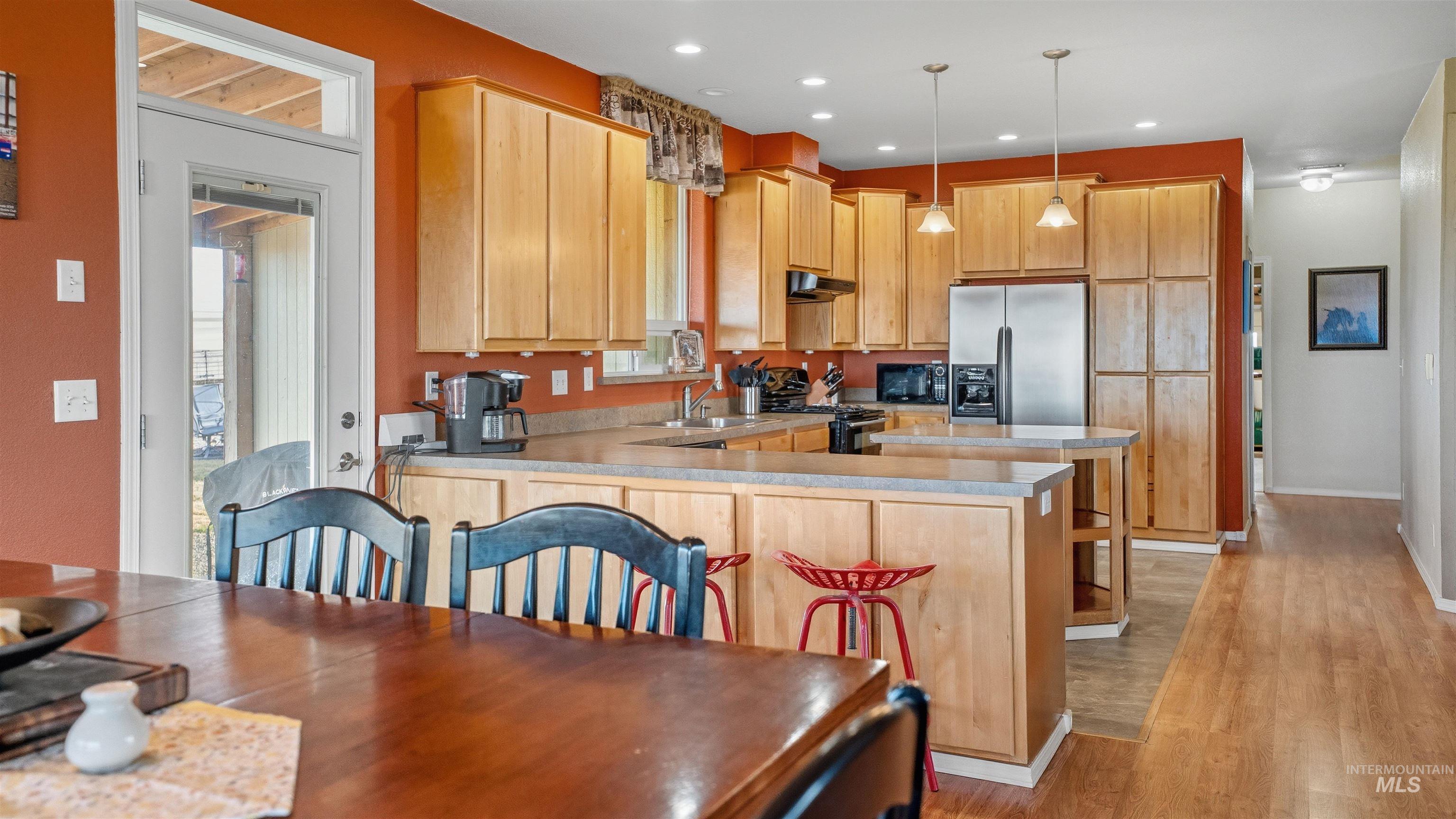 19397 Cloverland Road Asotin, WA 99402 - Photo 11 of 35 Kitchen with stainless steel fridge with ice dispenser, light countertops, gas stove, pendant lighting, and light wood finished floors