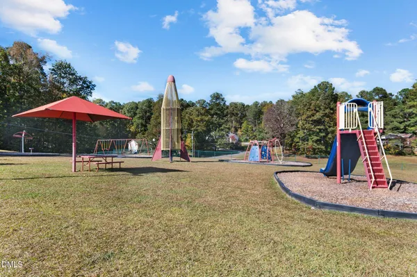 a swimming pool with a yard and trees in the background