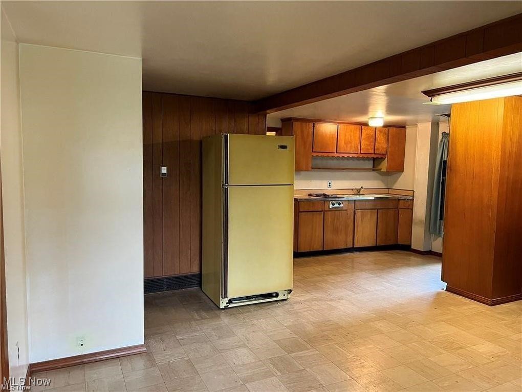 8581 Fair Road Strongsville, OH 44149 - Photo 16 of 20 Kitchen with light floors, freestanding refrigerator, brown cabinetry, wood walls, and light countertops