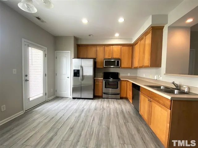 a kitchen with a sink wooden floor and stainless steel appliances