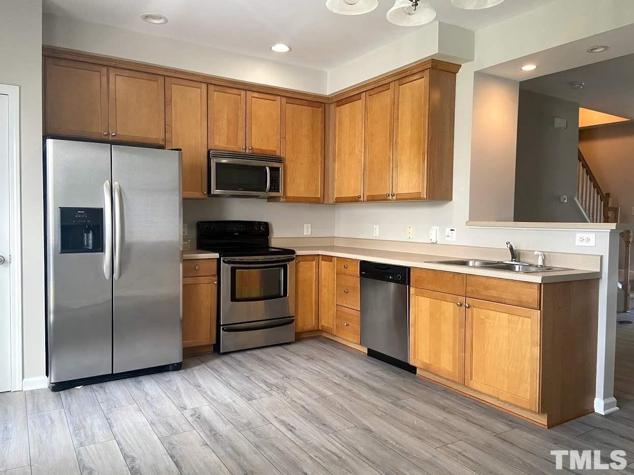 5105 Powell Townes Way Raleigh, NC 27606 - Photo 3 of 14 a kitchen with granite countertop wooden floors stainless steel appliances and a sink