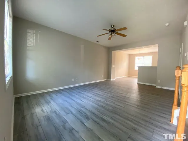 an empty room with wooden floor windows and ceiling fan