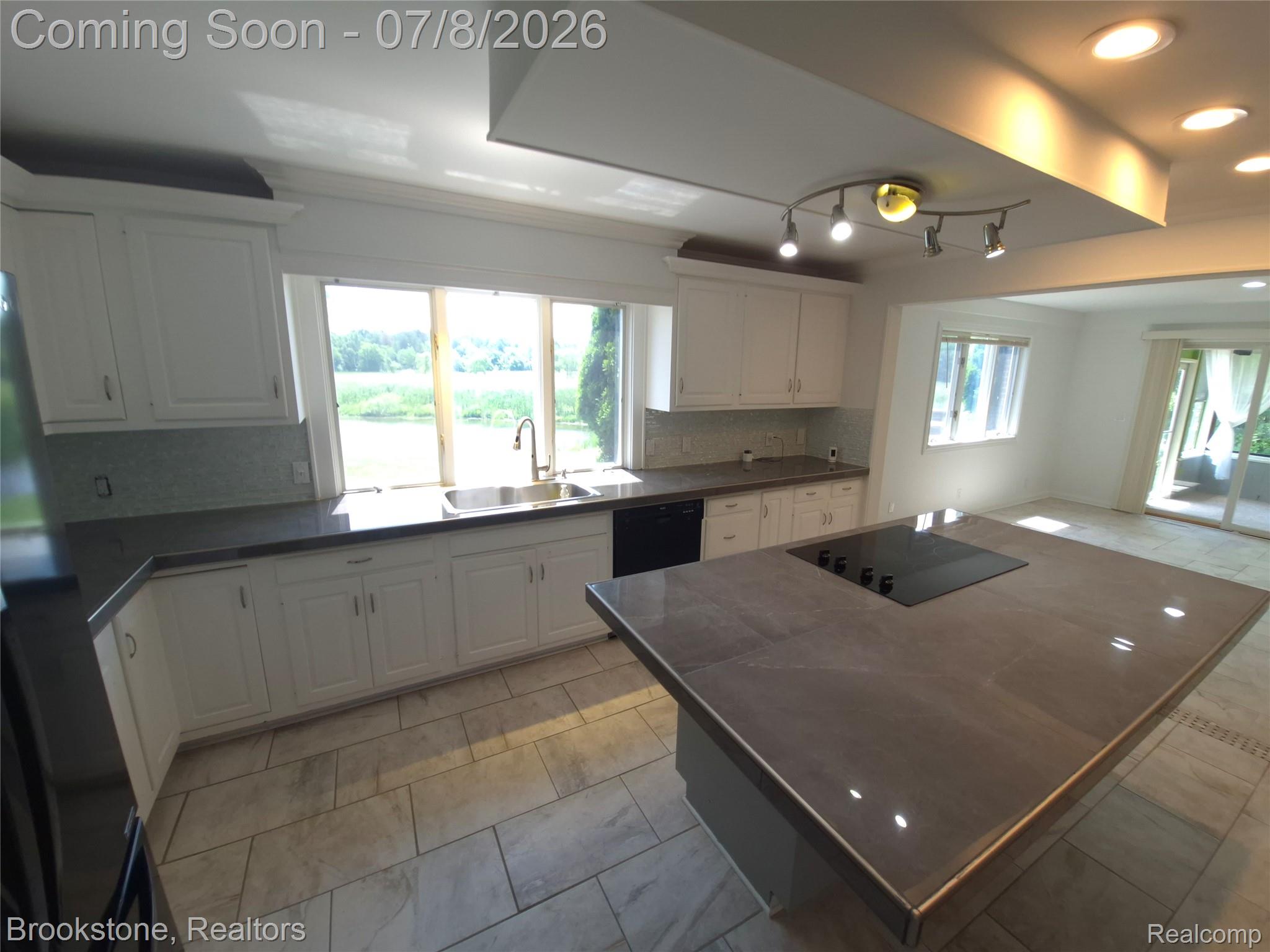 4140 South Henderson Road Davison, MI 48423 - Photo 23 of 98 Spacious kitchen featuring an expansive center island with an integrated cooktop, white shaker-style cabinetry, and dark countertops