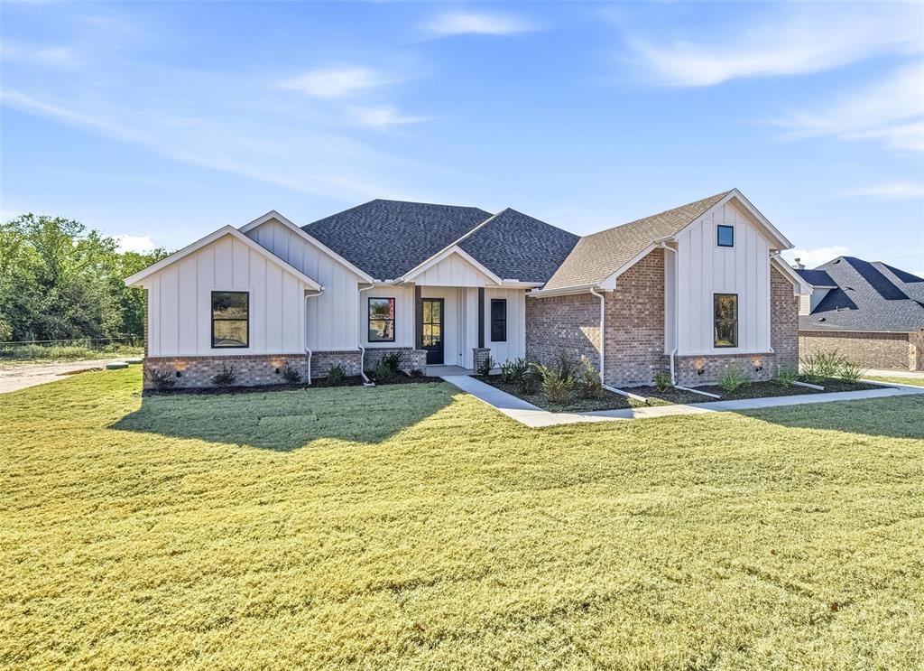 Modern inspired farmhouse featuring board and batten siding, a shingled roof, and a front yard