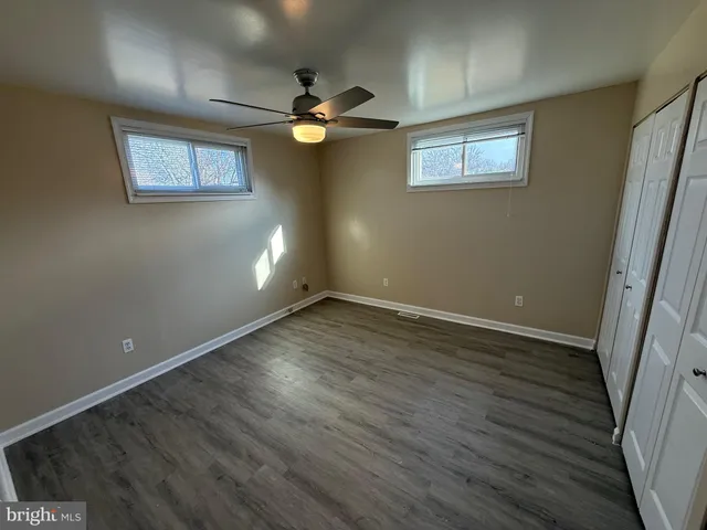 an empty room with wooden floor fan and windows