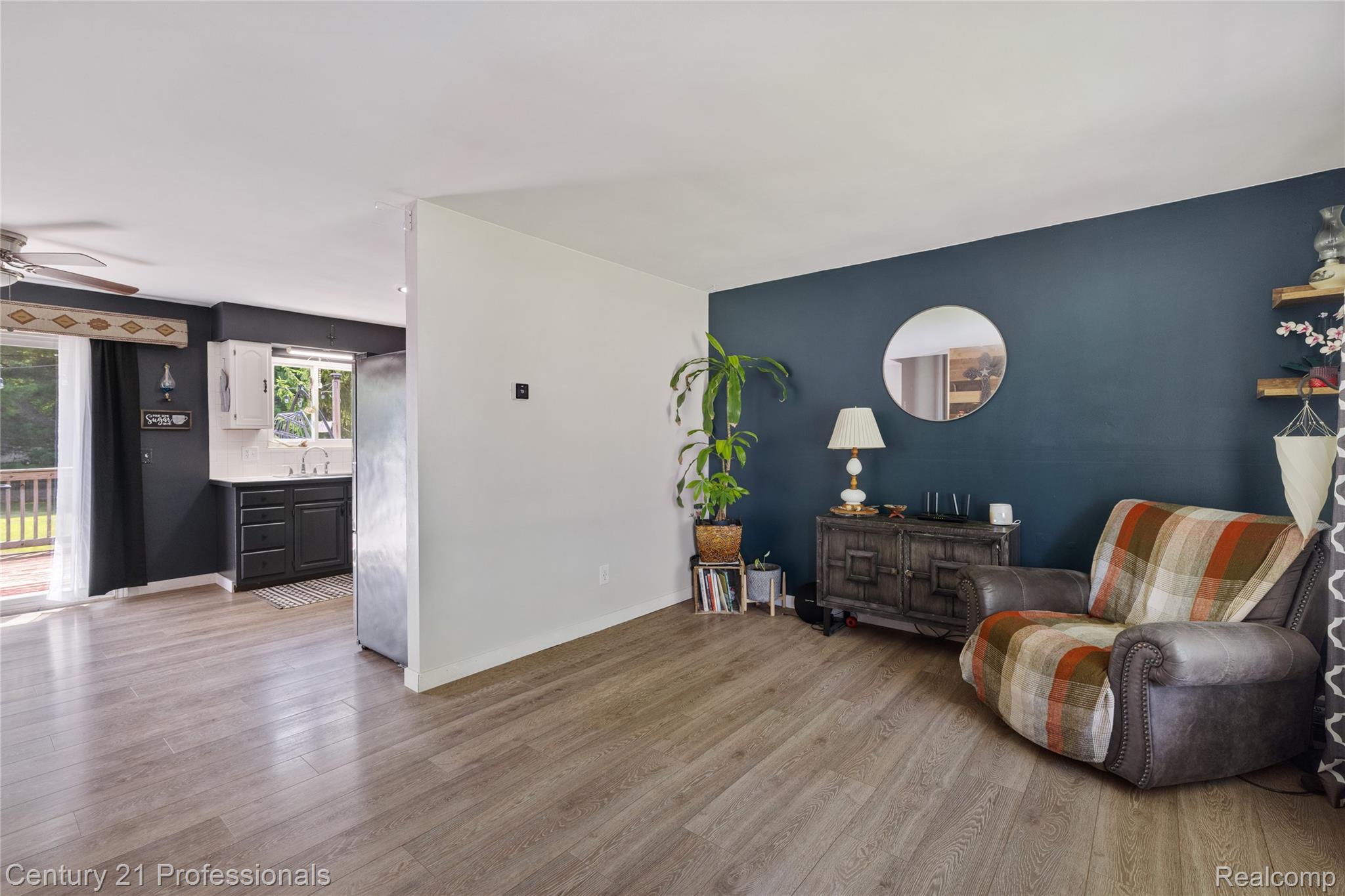 15037 Hogan Road Linden, MI 48451 - Photo 4 of 38 Open-concept living area featuring wood-finish flooring, a contemporary accent wall, and a seamless transition to the kitchen