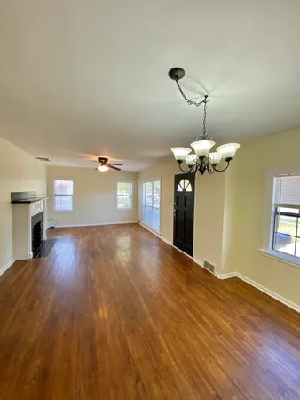 a view of a room with wooden floor ceiling fan and window