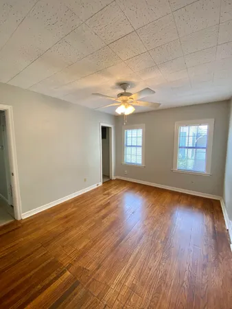 a view of an empty room with wooden floor and window