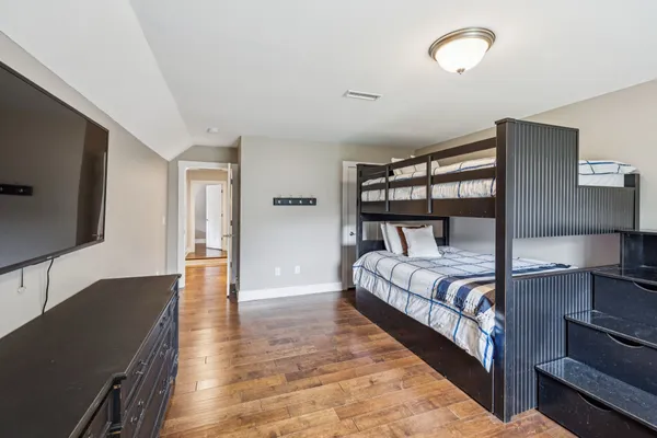 a spacious bedroom with a bed and a flat tv screen on the dresser