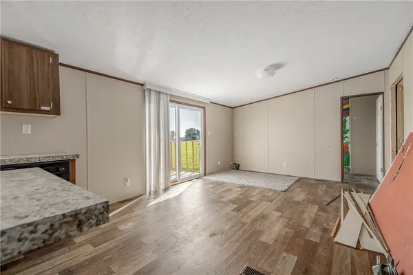 a view of a livingroom with wooden floor and kitchen space